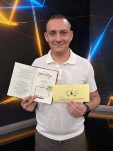 Усміхнений чоловік тримає відкритий підписаний Гаррі Поттер і жовтий конверт з листом