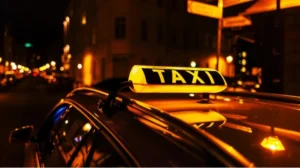 Освітлений жовтий знак TAXI на даху авто вночі на міській вулиці